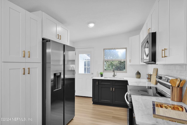 kitchen with white cabinetry, sink, appliances with stainless steel finishes, and light hardwood / wood-style flooring