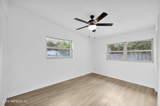 spare room with a textured ceiling, hardwood / wood-style flooring, vaulted ceiling, and ceiling fan