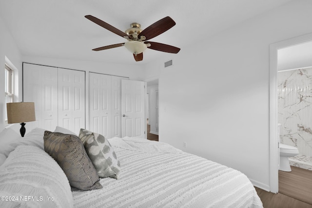 bedroom featuring wood-type flooring, connected bathroom, ceiling fan, and multiple closets