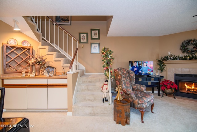 living room featuring a textured ceiling, sink, light colored carpet, and a tiled fireplace