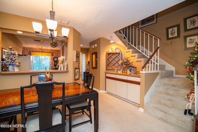 dining area featuring a textured ceiling, light colored carpet, and an inviting chandelier