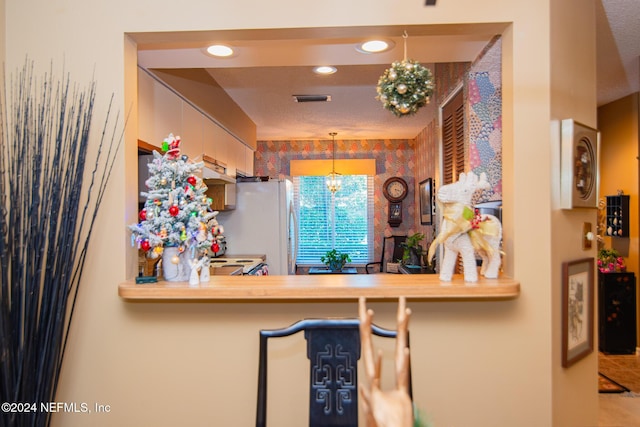 kitchen with a chandelier, hanging light fixtures, a textured ceiling, and white refrigerator