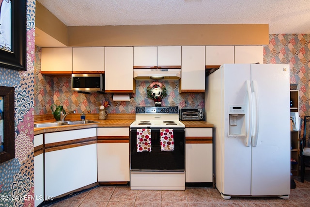 kitchen with white appliances, white cabinets, sink, a textured ceiling, and light tile patterned flooring