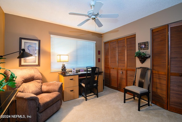 carpeted home office with ceiling fan and a textured ceiling