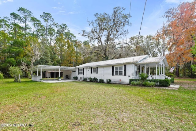 back of property with a carport and a lawn