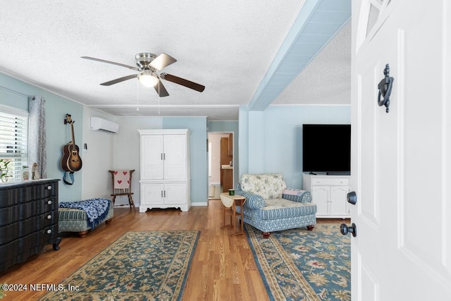 bedroom featuring wood-type flooring, a textured ceiling, a wall unit AC, and ceiling fan