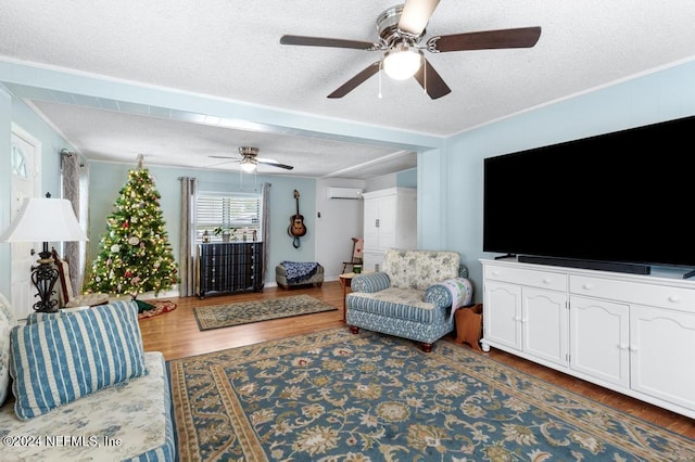 living room featuring an AC wall unit, ornamental molding, a textured ceiling, and hardwood / wood-style flooring