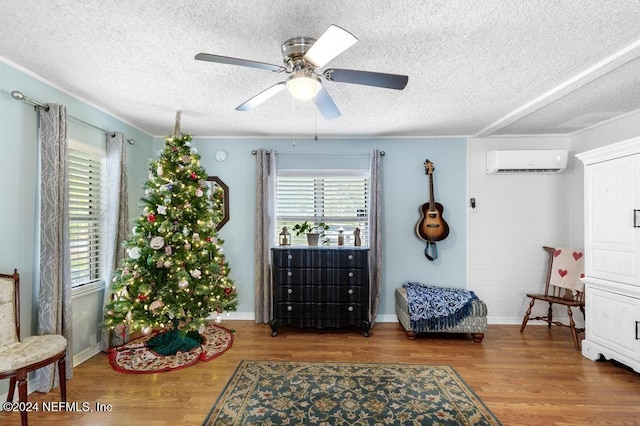 sitting room with a wall mounted air conditioner, a textured ceiling, and hardwood / wood-style flooring