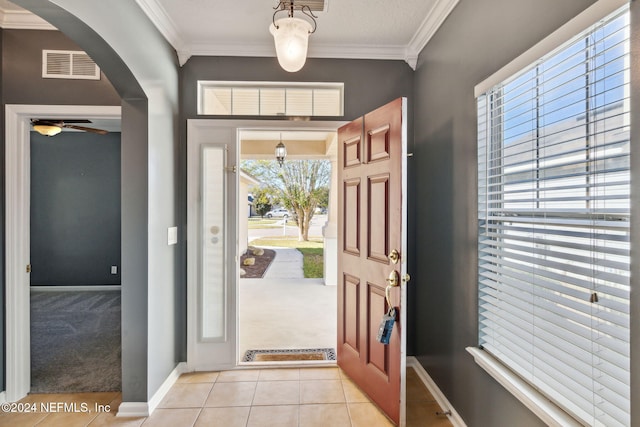 foyer featuring ceiling fan, light colored carpet, and crown molding