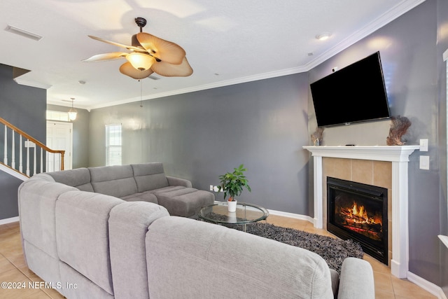 living room featuring crown molding, a fireplace, light tile patterned floors, and ceiling fan