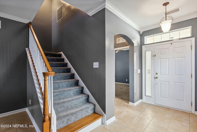 tiled entrance foyer with a textured ceiling and crown molding