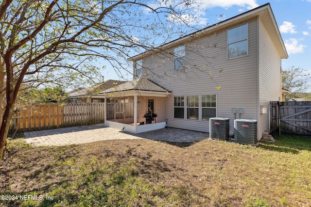 rear view of house with a lawn, a patio area, and central AC