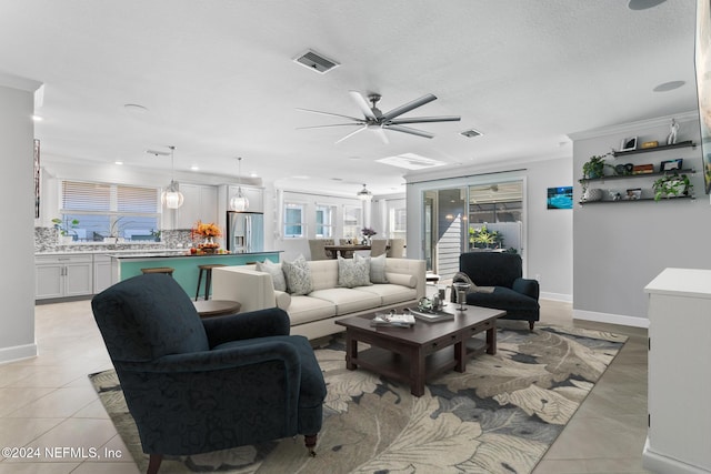 tiled living room with crown molding, ceiling fan, and a textured ceiling