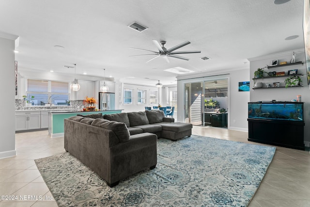 living room with light tile patterned floors, a textured ceiling, ceiling fan, and ornamental molding