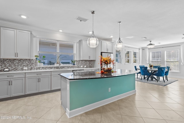 kitchen with gray cabinetry, crown molding, light tile patterned floors, a center island, and hanging light fixtures