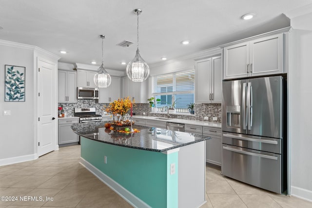 kitchen featuring dark stone counters, a kitchen island, stainless steel appliances, and ornamental molding