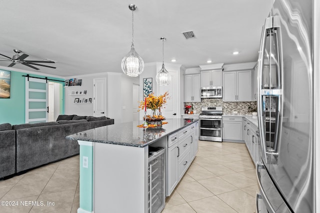 kitchen featuring appliances with stainless steel finishes, light tile patterned floors, a barn door, a center island, and white cabinetry