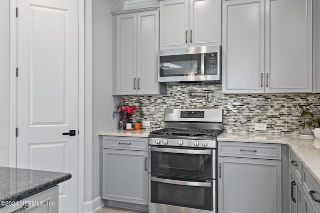 kitchen with light stone counters, backsplash, and appliances with stainless steel finishes