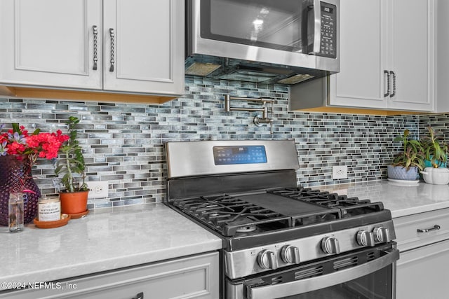 kitchen featuring appliances with stainless steel finishes, backsplash, and white cabinetry