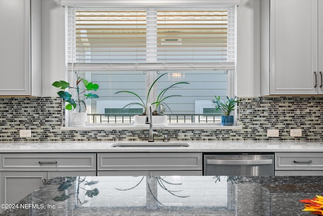 kitchen featuring dishwasher, sink, stone counters, and tasteful backsplash