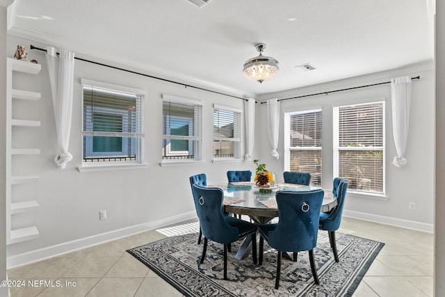 dining room with a chandelier, light tile patterned floors, and crown molding