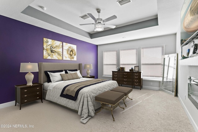 carpeted bedroom featuring a tray ceiling and ceiling fan