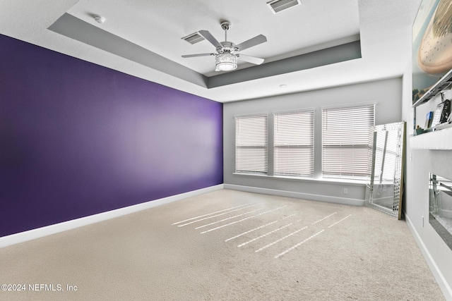 carpeted spare room featuring ceiling fan, a raised ceiling, and a textured ceiling