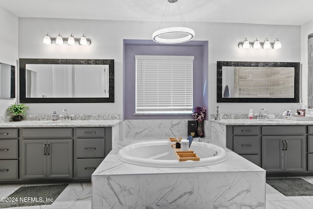 bathroom featuring vanity and a relaxing tiled tub