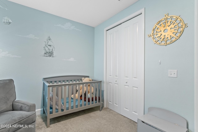 bedroom with a crib, light carpet, and a closet