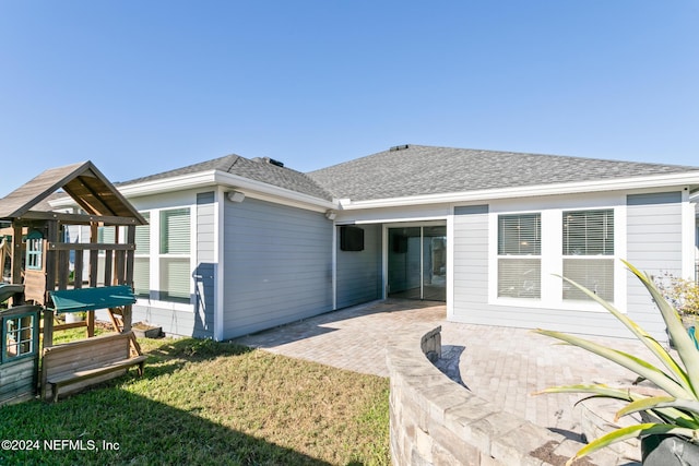 back of property with a playground, a patio area, and a yard