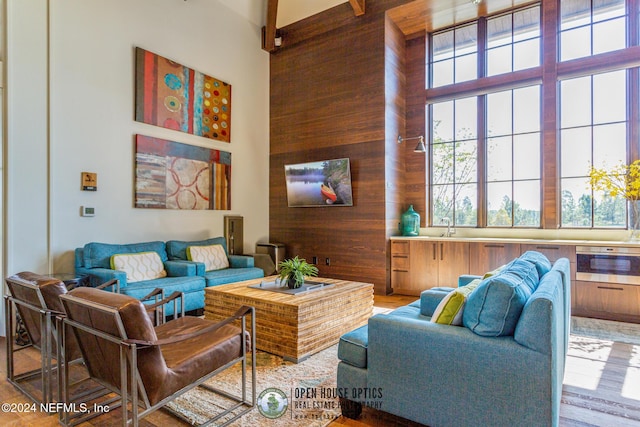 living room with wooden walls, a high ceiling, and hardwood / wood-style flooring