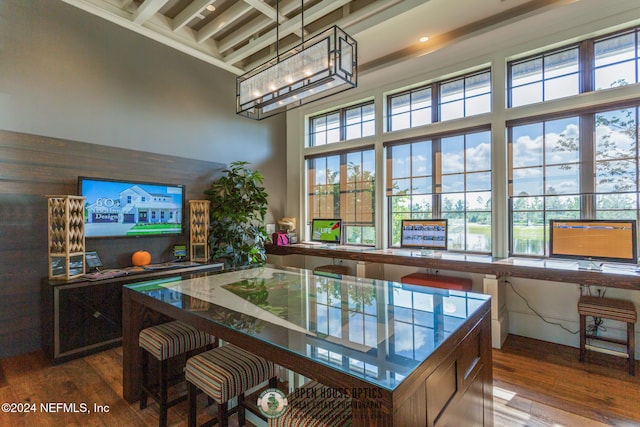 interior space with plenty of natural light, wood-type flooring, a towering ceiling, and a chandelier