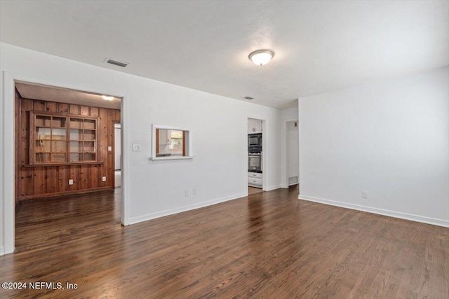 spare room featuring wooden walls and dark hardwood / wood-style floors