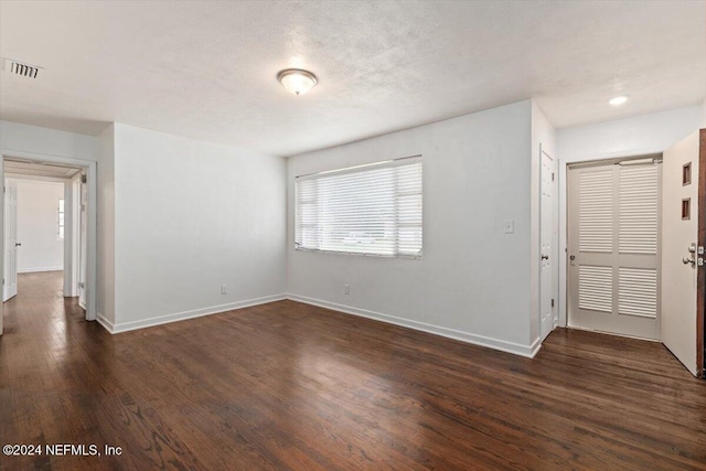 spare room featuring a textured ceiling and dark hardwood / wood-style floors