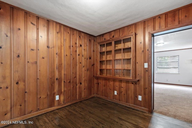 spare room featuring dark hardwood / wood-style floors, a textured ceiling, and wooden walls