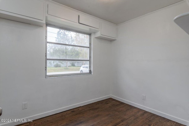 empty room with crown molding and dark hardwood / wood-style flooring