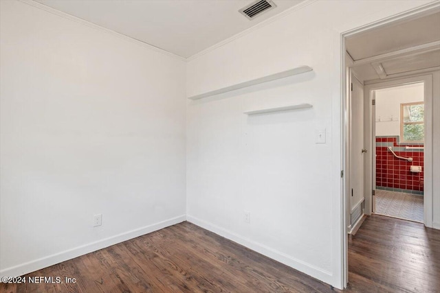 spare room with crown molding, dark wood-type flooring, and tile walls