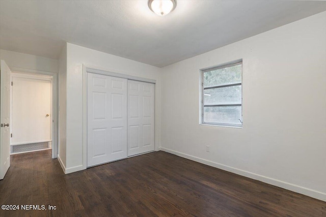 unfurnished bedroom with dark hardwood / wood-style flooring and a closet