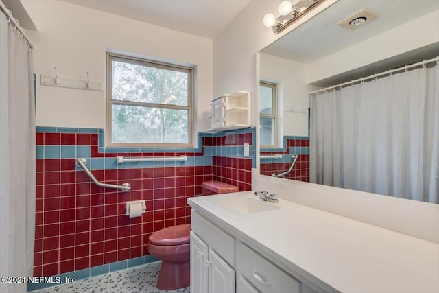 bathroom featuring vanity, tile walls, and toilet