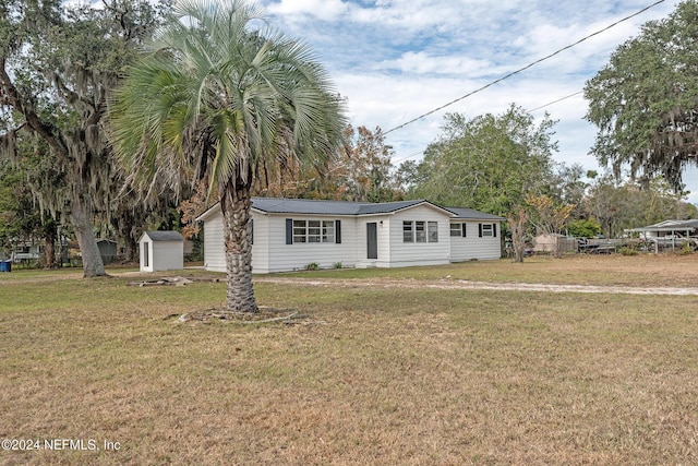 view of front of house with a front yard and a storage shed