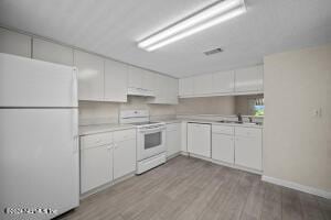 kitchen with light hardwood / wood-style flooring, white cabinets, and white appliances