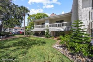 rear view of property featuring a lawn and a balcony