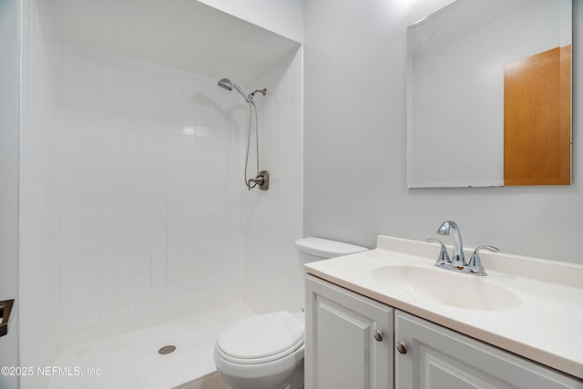 bathroom featuring vanity, toilet, and tiled shower