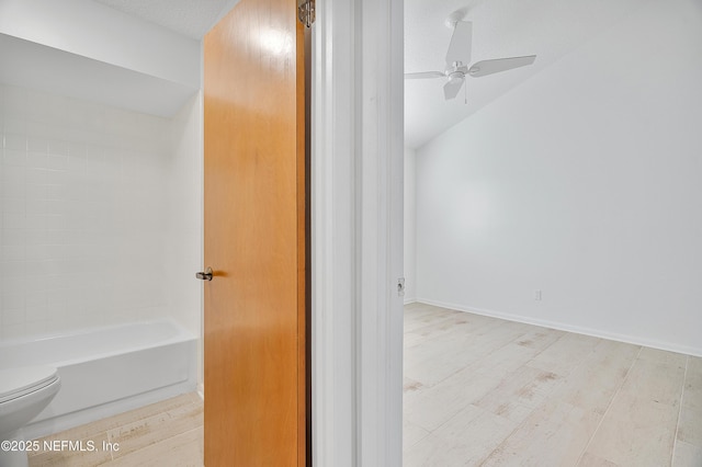 bathroom featuring vaulted ceiling, ceiling fan, toilet, a textured ceiling, and shower / bath combination