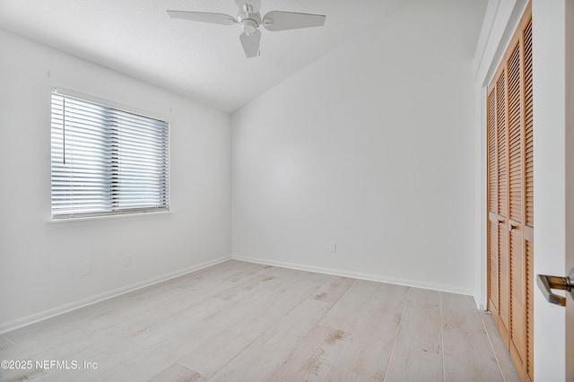 spare room with ceiling fan, vaulted ceiling, and light wood-type flooring