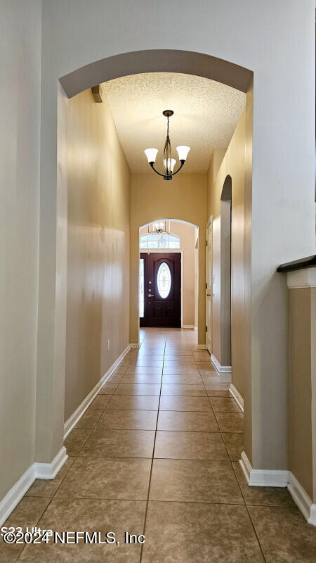 entryway with a chandelier, a textured ceiling, and tile patterned floors