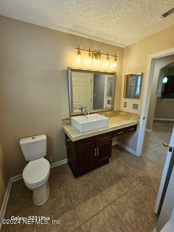 bathroom with tile patterned floors, vanity, toilet, and a textured ceiling