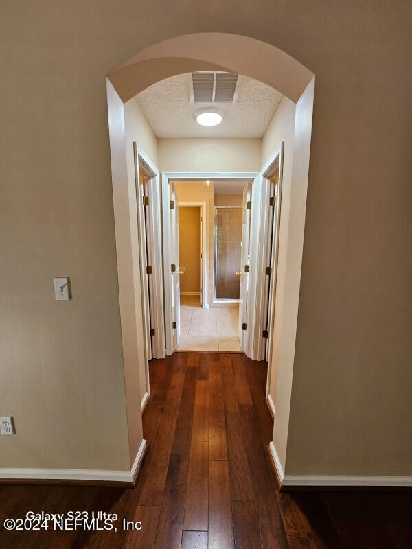 hallway featuring a textured ceiling and dark wood-type flooring