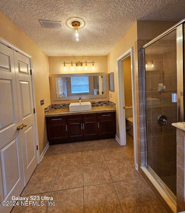 bathroom featuring tile patterned flooring, vanity, a textured ceiling, and toilet