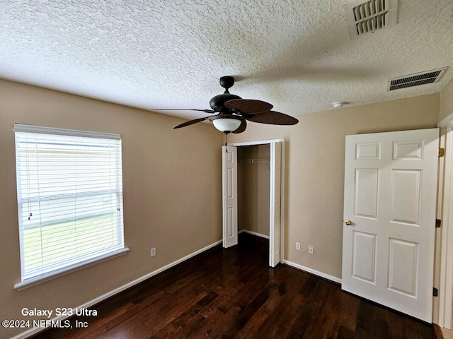 unfurnished bedroom featuring a closet, ceiling fan, dark hardwood / wood-style flooring, and a textured ceiling